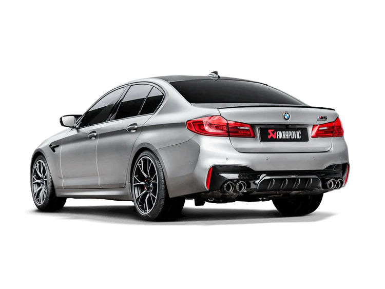 Near side rear view of a silver BMW M5 F90 with an Akrapovic Titanium exhaust with twin pipes each side, a carbon fibre tail pipe set & carbon fibre rear diffuser