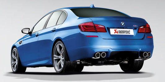 Near side rear view of a blue BMW M5 with an Akrapovic twin pipe each side exhaust & a carbon fibre tail pipe set fitted