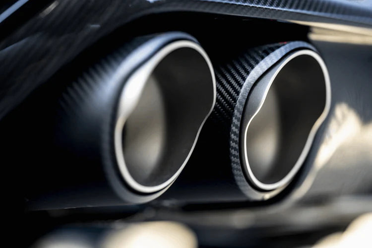 Close up view of a pair of carbon fibre exhaust tips fitted to a vehicle