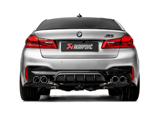 Rear view of a silver BMW M5 F90 with an Akrapovic exhaust, with twin pipes each side, & carbon fibre rear diffuser fitted