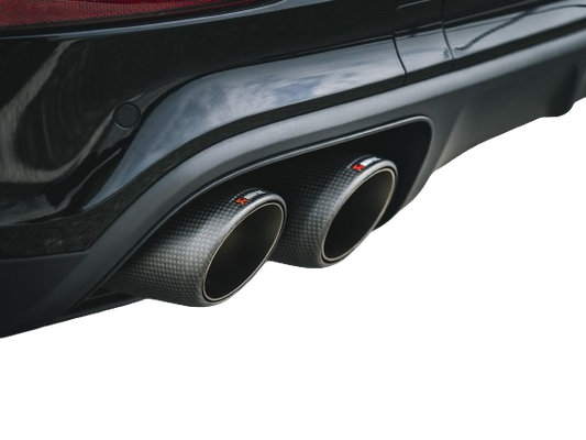 View of a pair of Akrapovič twin double round tail pipes with a carbon fibre finish fitted to a vehicle with a rear diffuser