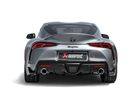 Rear view of a grey Toyota Supra A90 with an Akrapovič titanium exhaust, with twin pipes, fitted