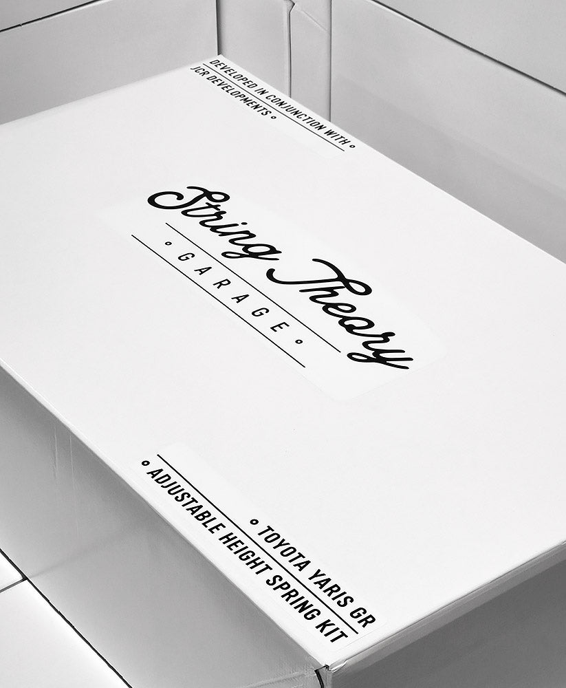 The image shows a white box with the label "String Theory Garage" in a stylized script font, indicating a branded product. It is noted to be an "Adjustable Height Spring Kit" for a "Toyota Yaris GR." There's also text suggesting collaboration with "Rallyworks." The presentation is sleek and professional, suggesting a specialized aftermarket part