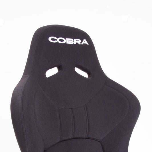Close up offside front view of a black Cobra Nogaro Club Sports seat with the Cobra name in white, on the headrest