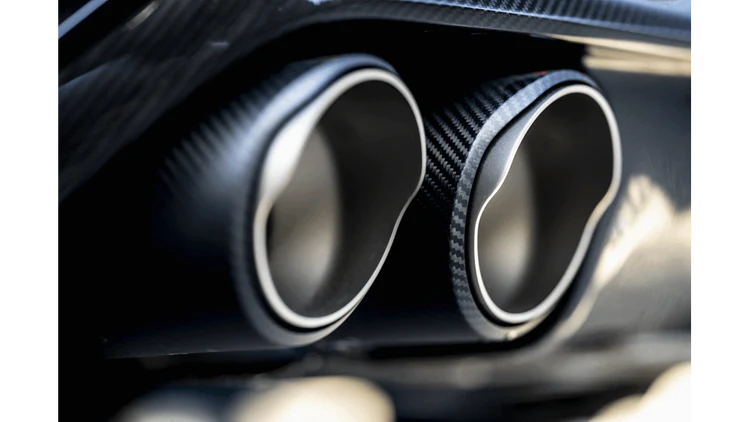 Close up view of a pair of Akrapovič carbon fibre exhaust tips fitted to a vehicle