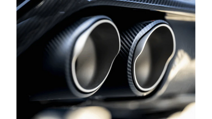 Close up view of a pair of Akrapovič carbon fibre exhaust tips fitted to a vehicle