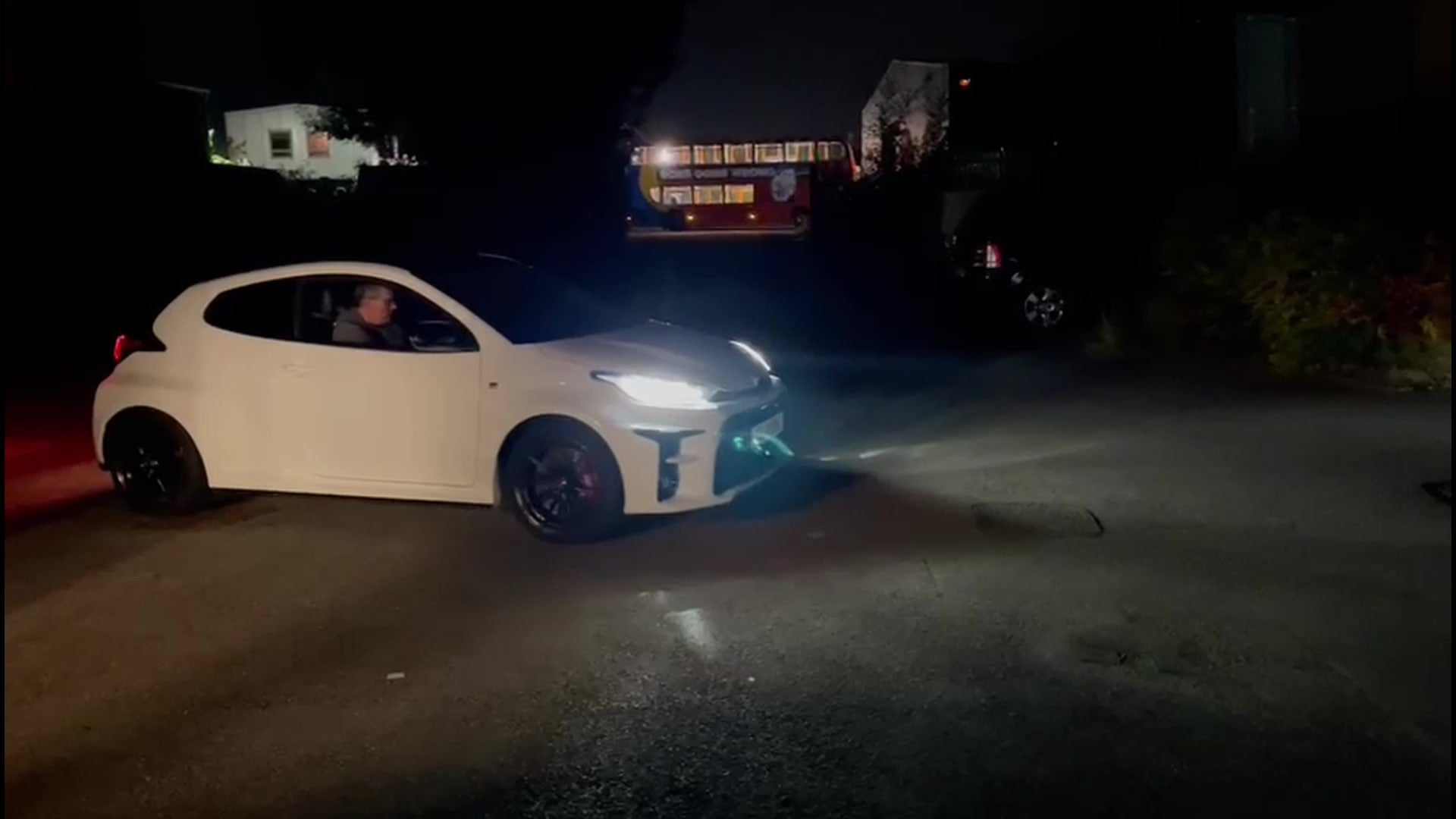 Image of a white Toyota GR Yaris in the dark with the lights on