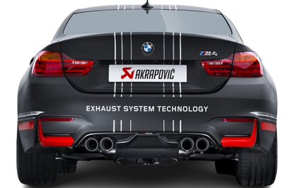 Rear view of a matt black BMW M4 with an Akrapovic exhaust, with twin pipes each side, & a carbon fibre rear diffuser fitted