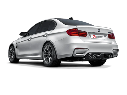 Near side rear view of a silver BMW M4 with an Akrapovic exhaust, with twin pipes each side, & a carbon fibre rear diffuser fitted