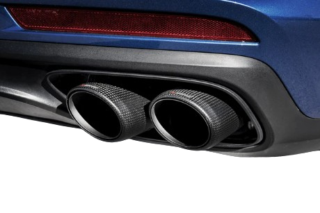 Close up view of a pair of Akrapovič tail pipes with a carbon fibre finish fitted to a blue car
