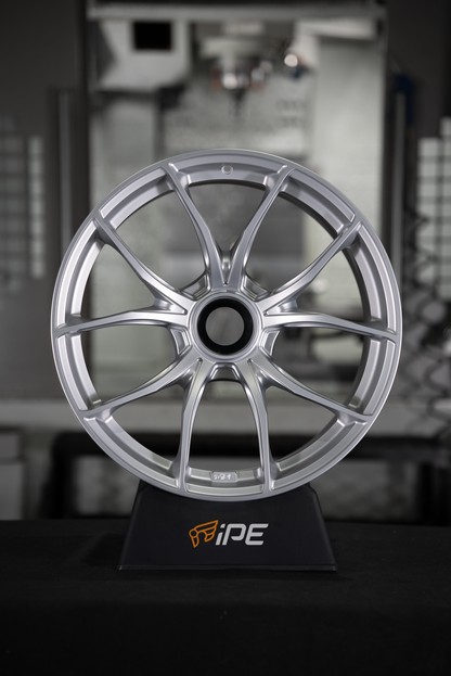 Front view of an IPE MFR-01 Magnesium wheel in silver with a multi-spoke design sitting on an IPE stand with a workshop setting in the background