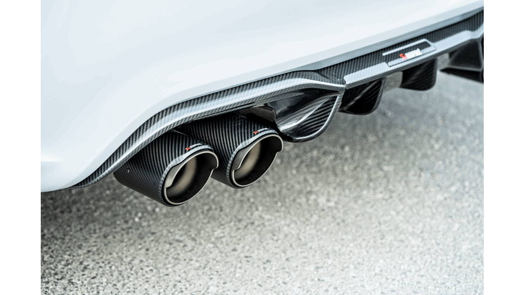 Close-up of a white car's rear with Akrapovic carbon fibre exhaust tips and diffuser