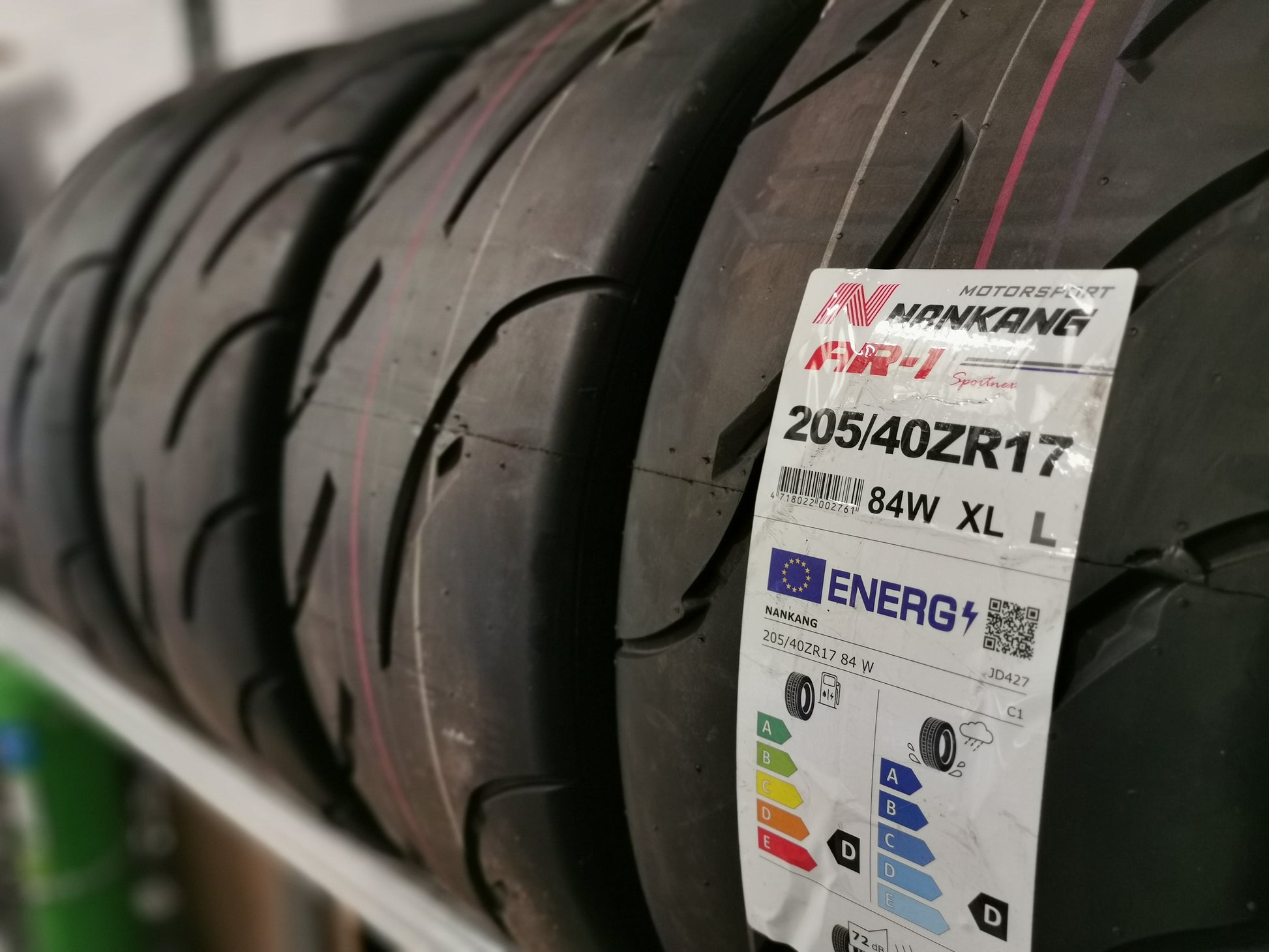 A set of Nankang AR-1 semi slick track day tyres on a rack with one having the label on, showing the size & ratings