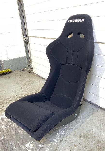 Nearside front view of a black Cobra Nogaro Club Sports seat with the Cobra name in white, on the headrest